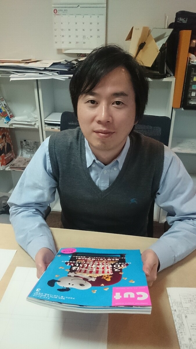 Masashi Kishimoto assis dans son atelier, tenant un exemplaire du magazine CUT, en 2015